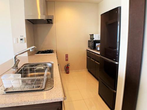 a kitchen with a dish drying rack in a sink at 真栄田グランブルー403 ~ Maeda Grand Blue 403 ~ in Onna