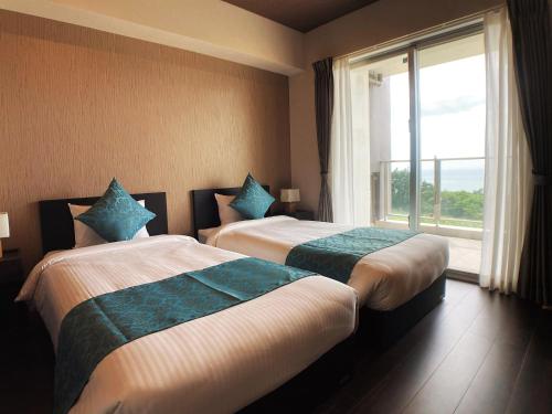 2 łóżka w pokoju hotelowym z oknem w obiekcie 真栄田グランブルー403 ~ Maeda Grand Blue 403 ~ w mieście Onna
