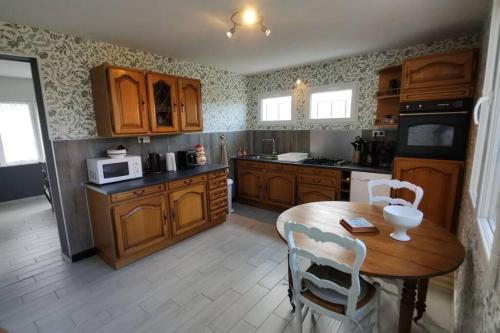une cuisine avec des armoires en bois et une table avec des chaises dans l'établissement Le Gîte des 4 Saisons Maison de vacances avec parking et jardin, à Saint-Omer