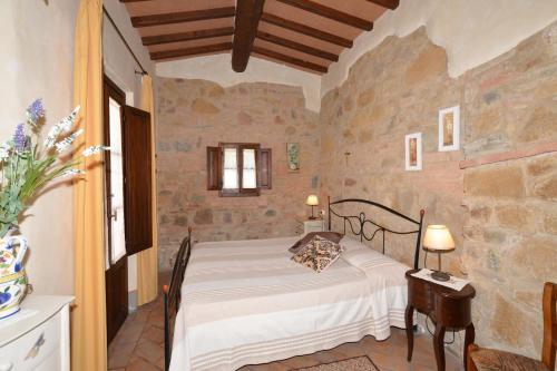 1 dormitorio con 1 cama en una habitación de piedra en Villa Casacheta, en Montaione