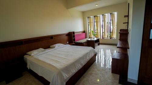 a bedroom with a large bed and two windows at The Janan Villa in Sanur