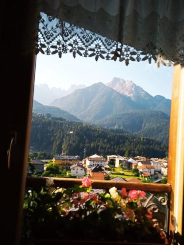 a view of mountains from a window with flowers at La Mansarda in Lozzo Cadore