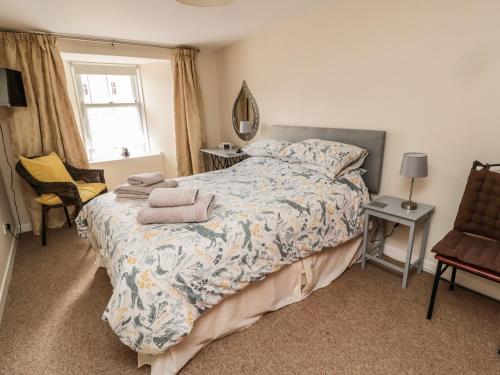 a bedroom with a bed and a chair and a window at Stable Lodge in Coldstream