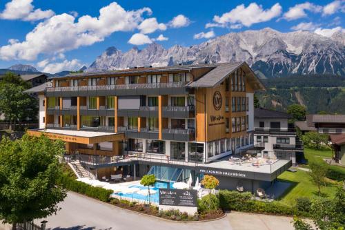 an image of a hotel with mountains in the background at Apart & Suiten Hotel WEIDEN in Schladming