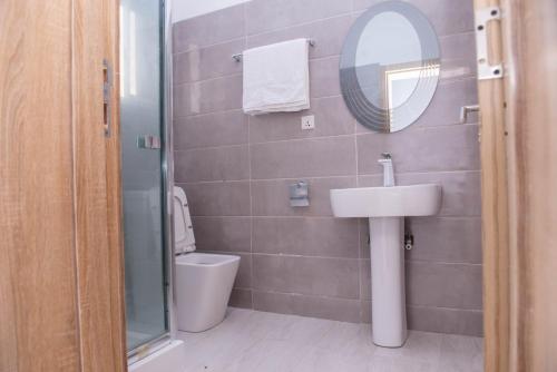 a bathroom with a sink and a mirror and a toilet at House4 in Lekki