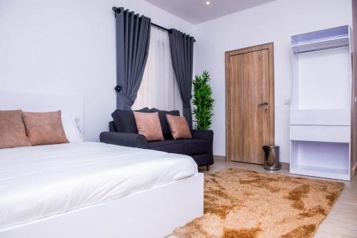a bedroom with a bed and a couch and a window at House4 in Lekki