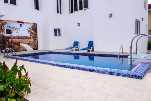 a swimming pool with two blue chairs next to a building at House4 in Lekki