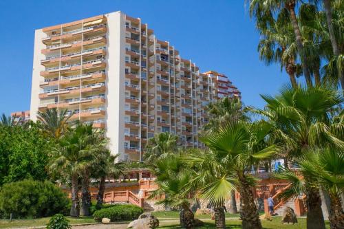 un grand bâtiment avec des palmiers devant lui dans l'établissement Apartamento Tamarindos II, à Benalmádena