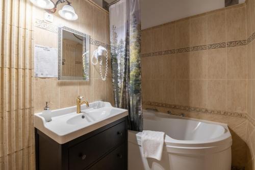 a bathroom with a sink and a toilet and a tub at Kőkapu Vadászkastély és Hotel & Apartments in Nagyhuta