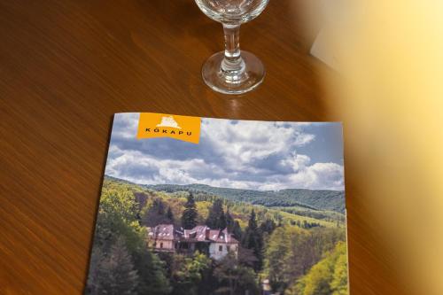 a magazine sitting on a table next to a glass at Kőkapu Vadászkastély és Hotel & Apartments in Nagyhuta