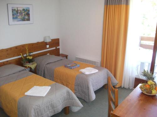 Cette chambre comprend 2 lits et une table. dans l'établissement VVF Jura Les Rousses, à Prémanon