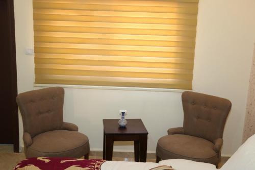 two chairs and a table in a room with a window at Petra Stones Inn in Wadi Musa