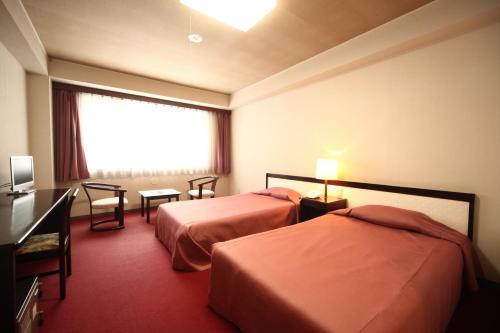 a hotel room with two beds and a window at Hotel Towadaso in Towada