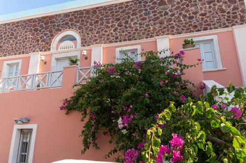 a pink building with flowers in front of it at The Museum Project Oia in Oia