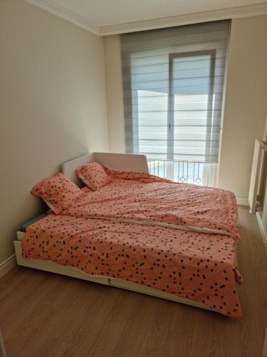 a bedroom with a bed with a red comforter and a window at Sweet Marmara in Beylikduzu