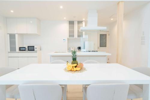 a white kitchen with a table with a pineapple on it at Villa Capri Miyakojima in Miyako-jima