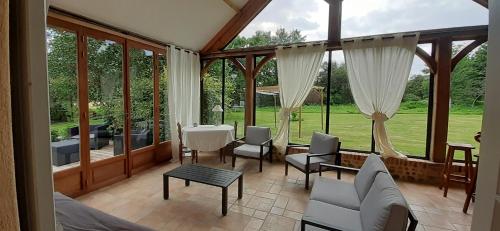 sala de estar con ventanas, mesa y sillas en La maison d'amis du moulin en La Chapelle-Viel