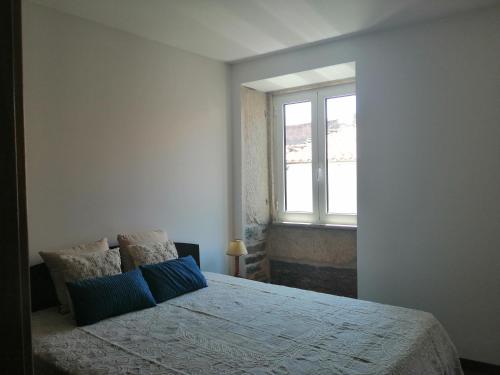 a bedroom with a bed with blue pillows and a window at Casa da Muralha in Vila Nova de Foz Coa