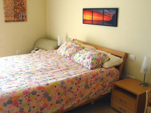 ein Schlafzimmer mit einem Bett mit einer bunten Bettdecke in der Unterkunft Ático Residencial Los Patios, Playa Médano, zona windsurf in El Médano