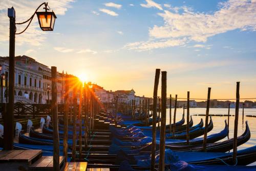 a row of gondolas in a canal at sunset at Albergo Casa Peron in Venice