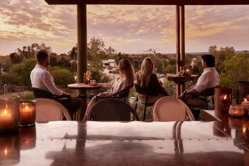 a group of people sitting at a table in a restaurant at Victoria Falls River Lodge in Victoria Falls