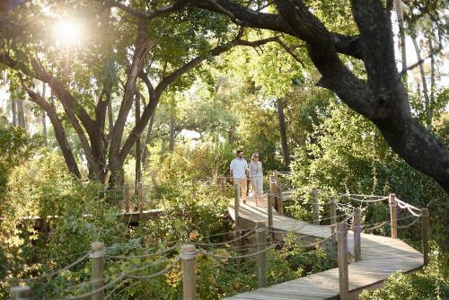 two people walking on a wooden bridge in a park at Victoria Falls River Lodge in Victoria Falls