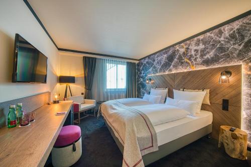 um quarto de hotel com uma cama grande e uma secretária em FourSide Hotel Salzburg em Salzburgo