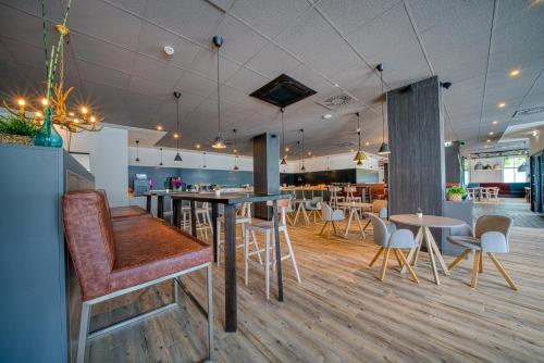 a restaurant with tables and chairs and a bar at FourSide Hotel Salzburg Messe, Trademark Collection by Wyndham in Salzburg