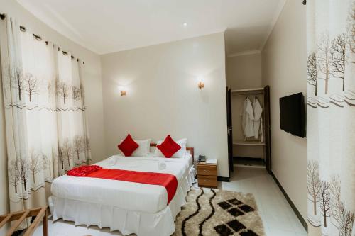 a bedroom with two white beds and red pillows at Panama Garden Resort in Moshi