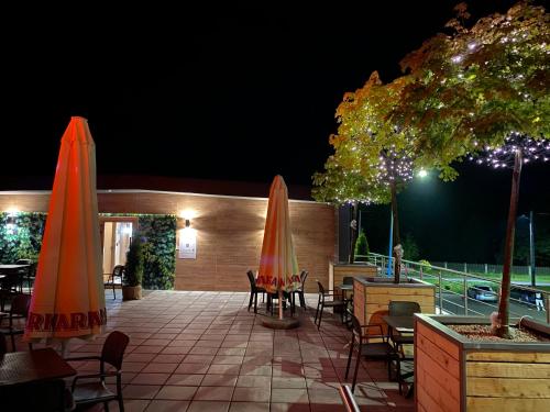 a patio with tables and chairs and umbrellas at night at Apartamenty Green Place in Kańczuga
