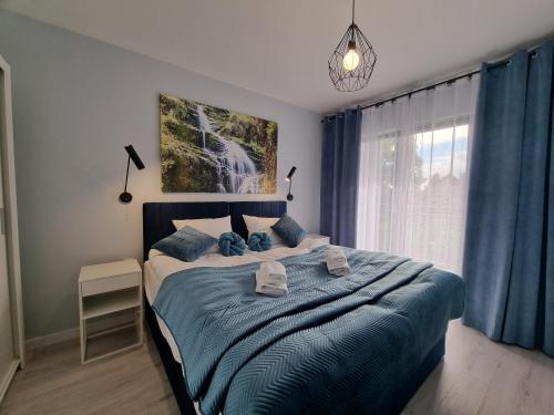 a bedroom with a bed with blue sheets and a window at Apartament Szmaragdowy w Karpatia - 5D Apartamenty in Karpacz