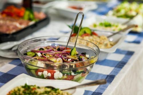 a salad in a bowl on a table with plates of food at Hotel Olivia in Gdańsk