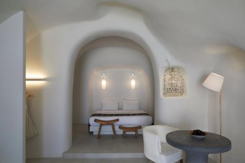 una camera con letto, tavolo e sedie di Elysian Santorini a Oia