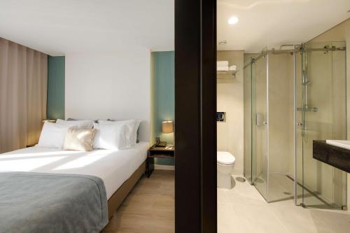 a bedroom with a bed and a bathroom with a shower at SDivine Fatima Hotel, Congress & Spirituality in Fátima