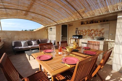 - une table en bois avec des assiettes roses sur la terrasse dans l'établissement Maison confortable à Villeneuve-lès-Avignon, plancha incluse, à Villeneuve-lès-Avignon