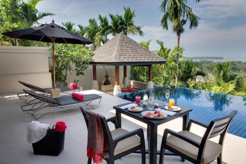 a patio with a table and chairs next to a pool at The Pavilions Phuket in Bang Tao Beach
