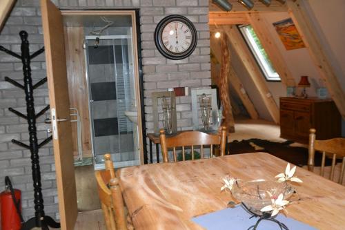 a dining room with a table and a clock on a brick wall at La Bulle Du Trappeur (Chevaux bienvenus) in Pondrôme