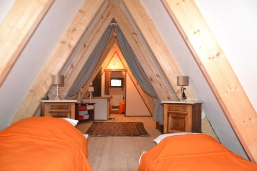 a bedroom with two beds and a pointed ceiling at La Bulle Du Trappeur (Chevaux bienvenus) in Pondrôme