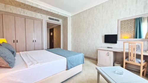 a bedroom with a bed and a desk and a tv at X Life Hotel Sarıgerme 15 - Adult Hotel in Sarigerme
