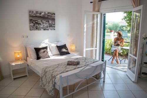 a bedroom with a bed and a woman sitting on a patio at Seaside Villa Alexandra,Acharavi. in Acharavi