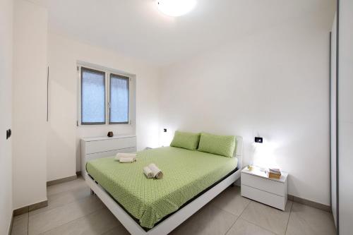 Un dormitorio blanco con una cama verde y una ventana en Appartamento 3 Il Tornante, en Nesso