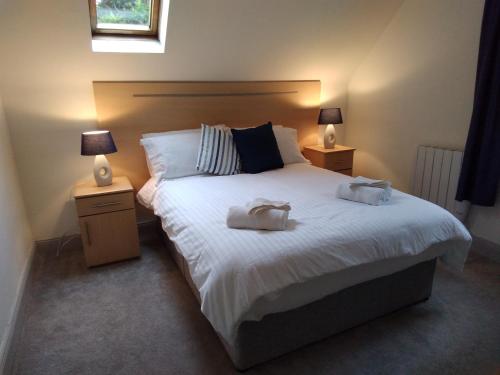 een slaapkamer met een groot wit bed met 2 lampen bij 43 Reidhlean Clifden Glen in Galway