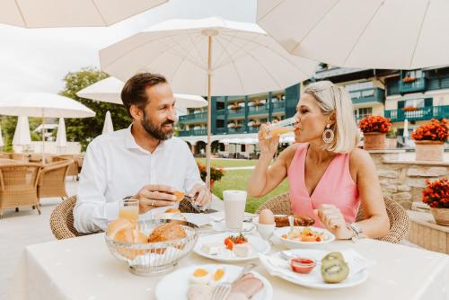a man and woman sitting at a table eating food at Hotel Friesacher in Anif