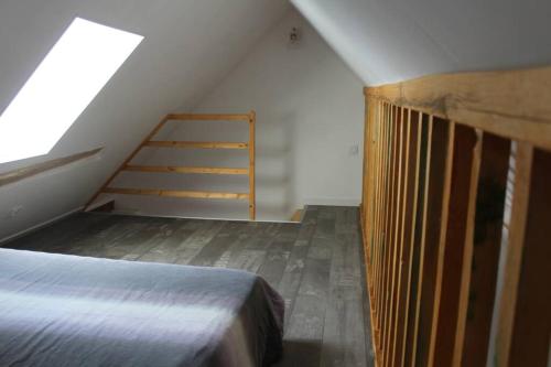 Cette chambre mansardée comprend un lit et une échelle. dans l'établissement Studio neuf proche d'Alençon et Le mans, à Lonrai