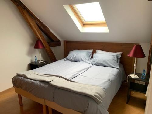 a bedroom with a large bed with a skylight at Le logis de l'Epte in Saint-Clair-sur-Epte
