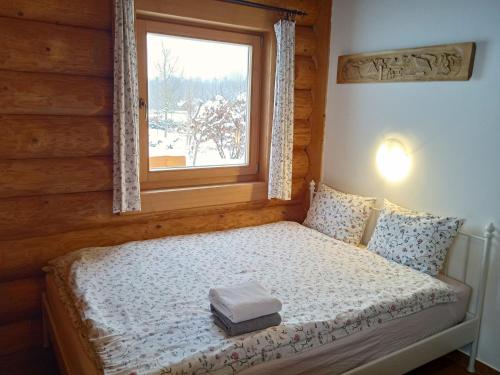 a bed with a book on it in a room with a window at Srub Javorná - apartmány Šumava in Javorná