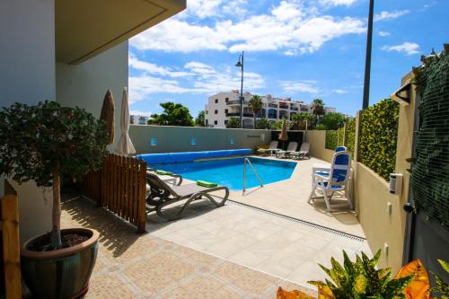 a patio with a swimming pool and two chairs at Villa Golf y Mar in San Miguel de Abona