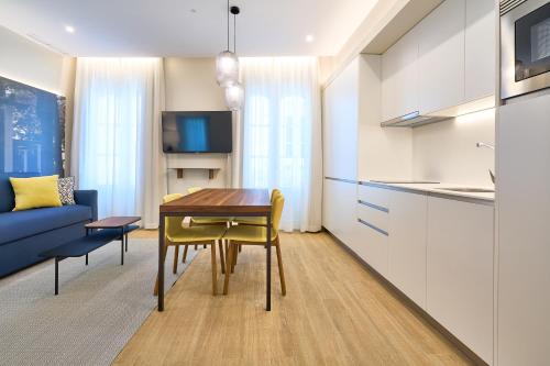 a kitchen and living room with a table and a blue couch at Tandem Pópulo in Cádiz