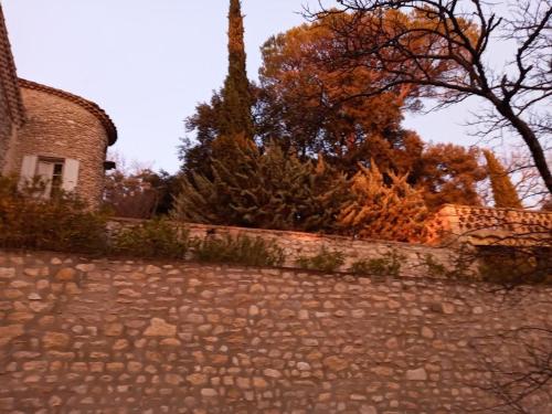 a stone wall next to a building and trees at Domaine La Tour - SPA - Jacuzzi - Sauna - Massage - 4 SAISONS - Piscine Chauffée Toute l'année - Heated POOL - 800m City Centre Nyons in Nyons