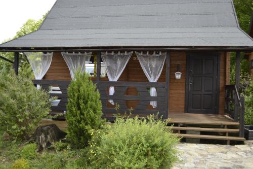 a small wooden cabin with a porch and a door at Chata Starych Znajomych in Sanok